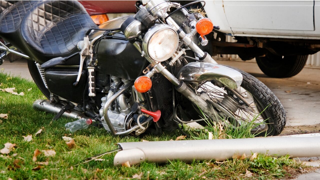 crashed motorcycle cruiser laying next to grass